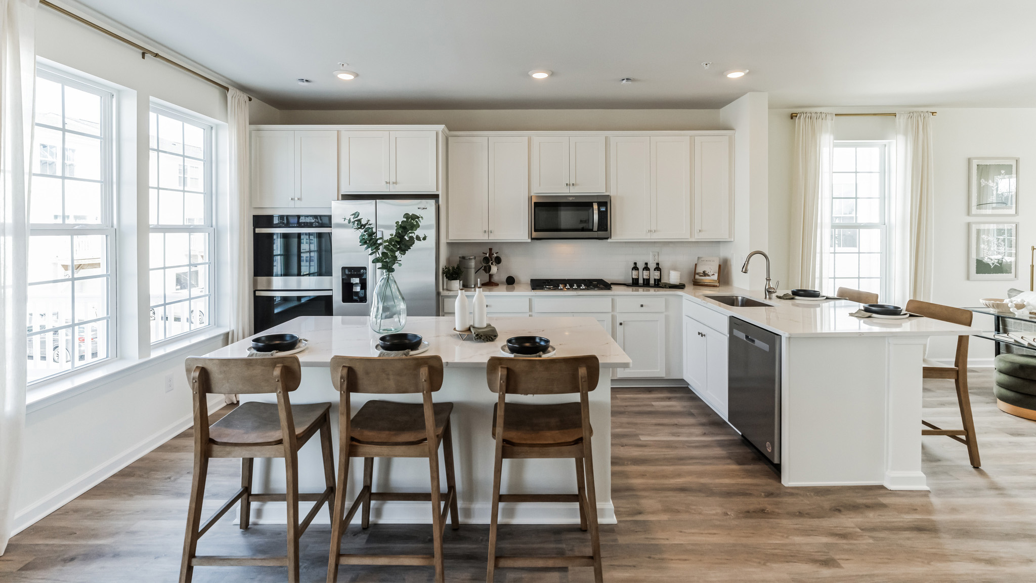 Spacious gourmet kitchen with large island, white and gray marble counter tops, and white cabinetry.
