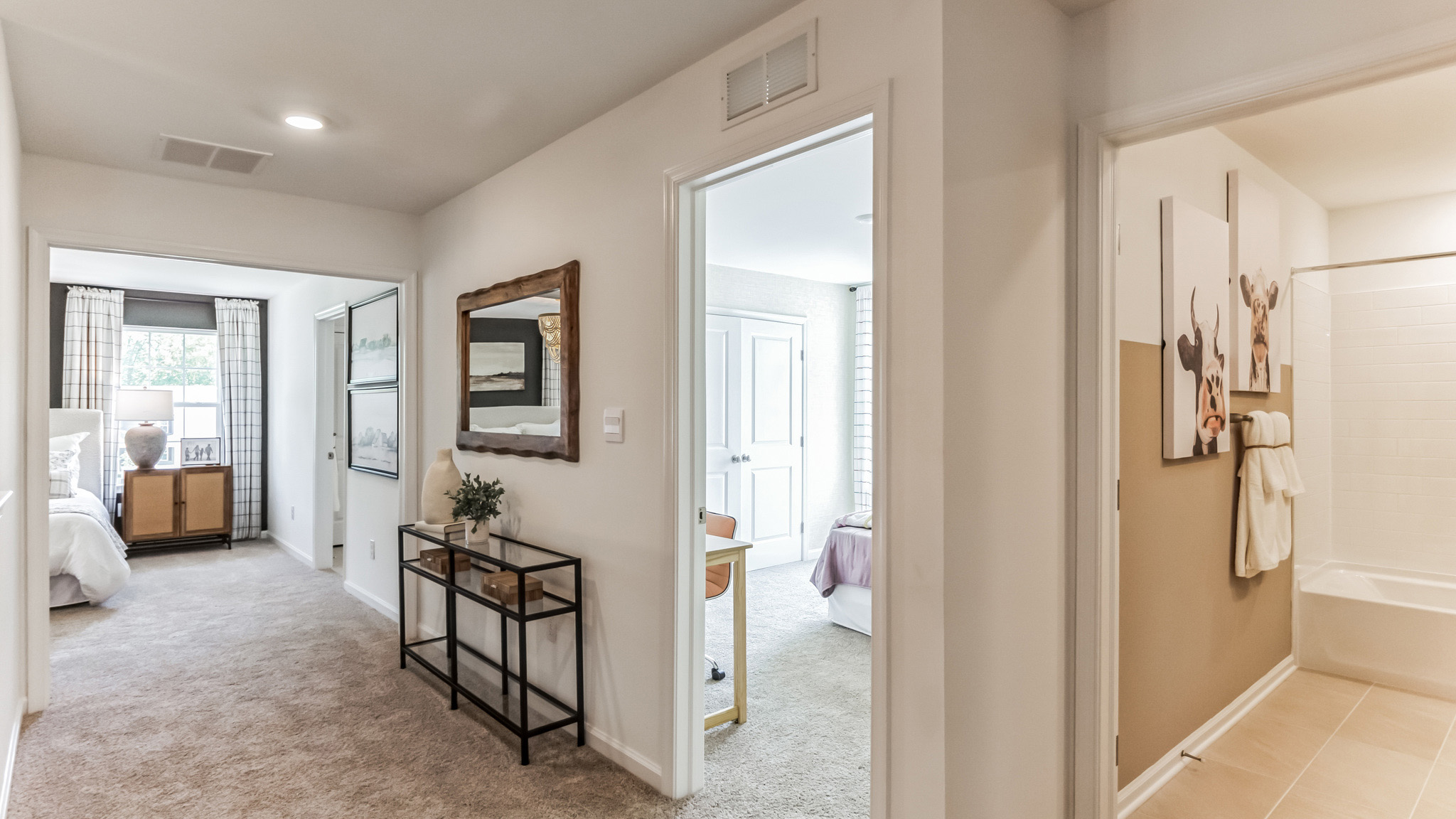 Upstairs hallway two bedrooms and a peek into a full bath with a double sink tan vanity.
