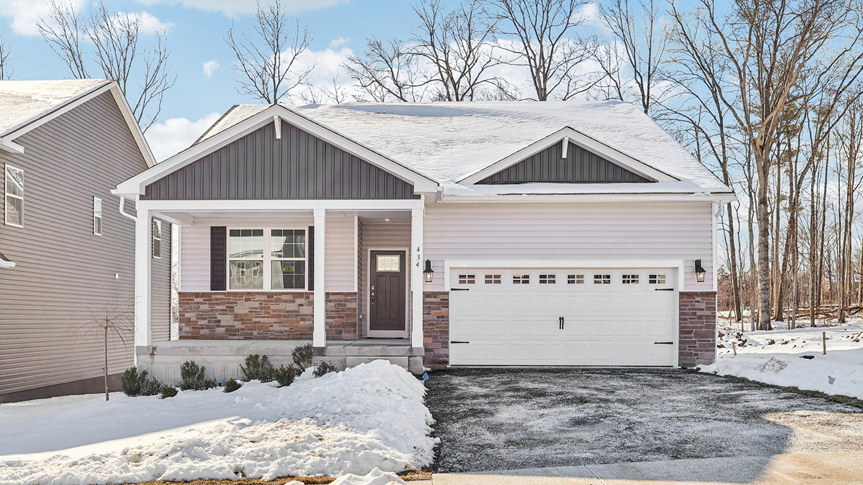 Exterior front image of the single story ranch home with sterling horizontal paneling and ironstom vertical paneling, dakota ledge stone kneewall, and a white two car garage.
