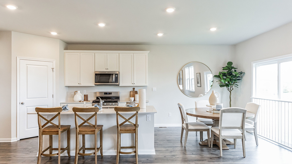 Kitchen with large island and white cabinetry with dining area to the right.