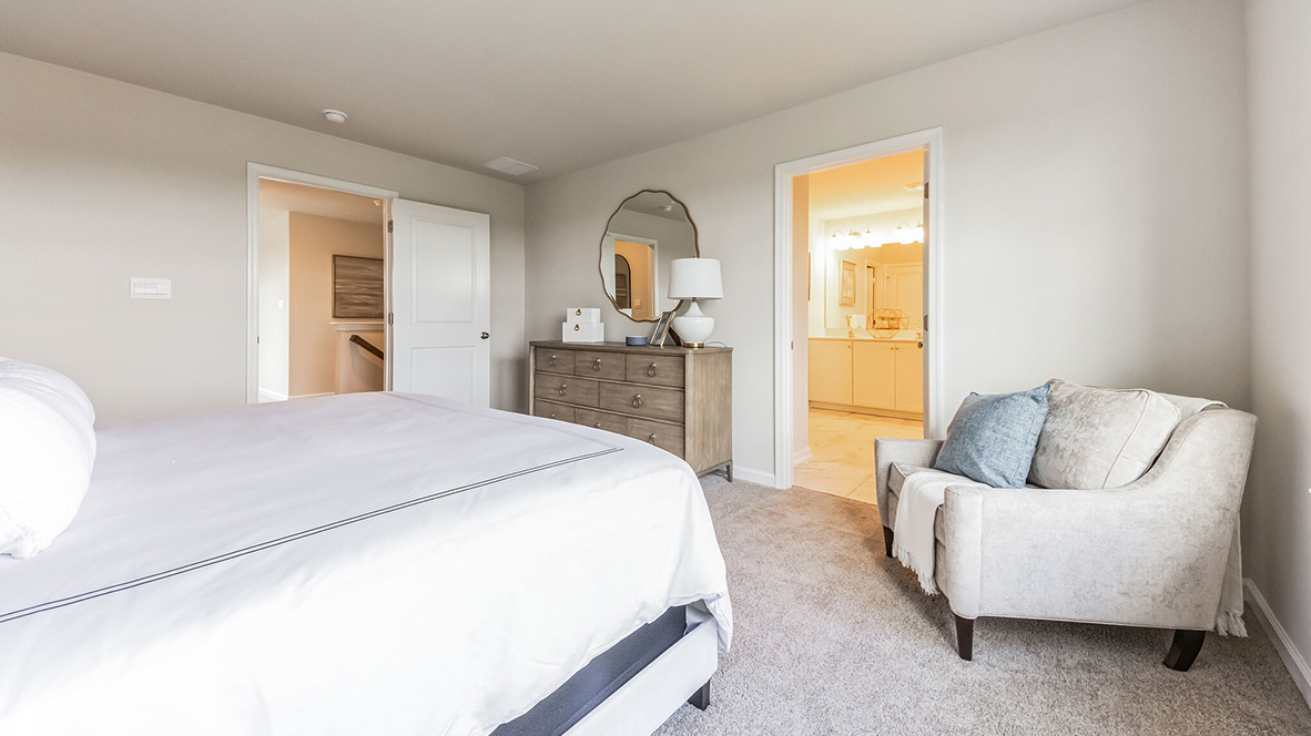 Different view of bedroom with two double windows and peek inside the connecting bathroom.
