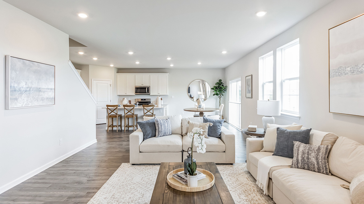 Different view of the living area standing in front of where a tv could go, overseeing the kitchen and dining area in the back of the image.