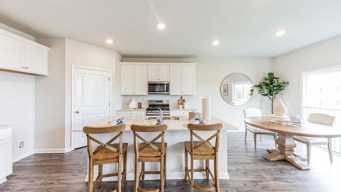 Kitchen with large island and white cabinetry with dining area to the right.