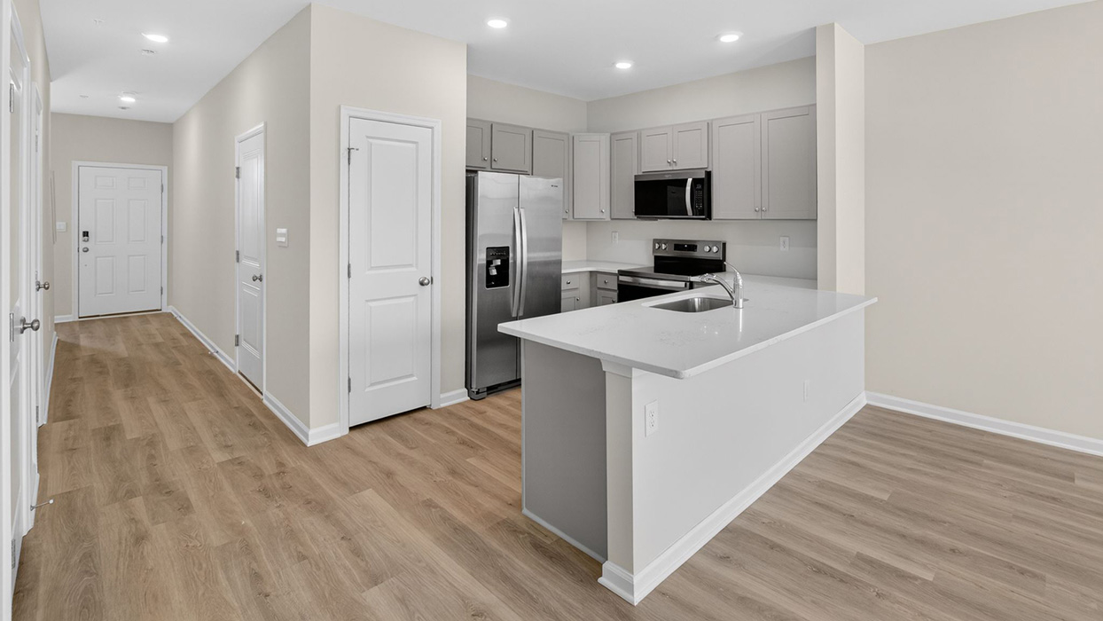 The kitchen area and pantry closet with part of the living area on the right.