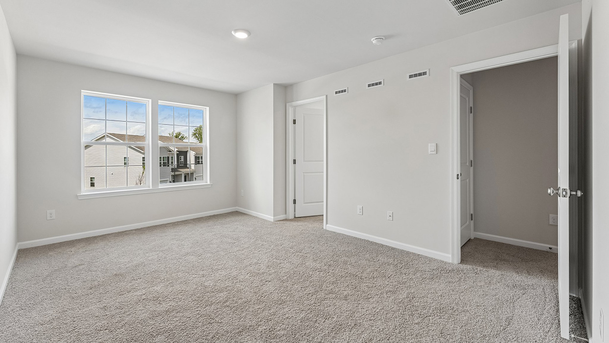 Bedroom with large windows, neutral walls, and doorway leading to additional interior spaces