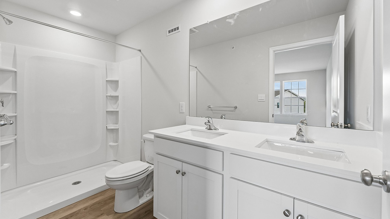Bathroom with dual sink vanity, large mirror, and walk-in shower with built-in shelving