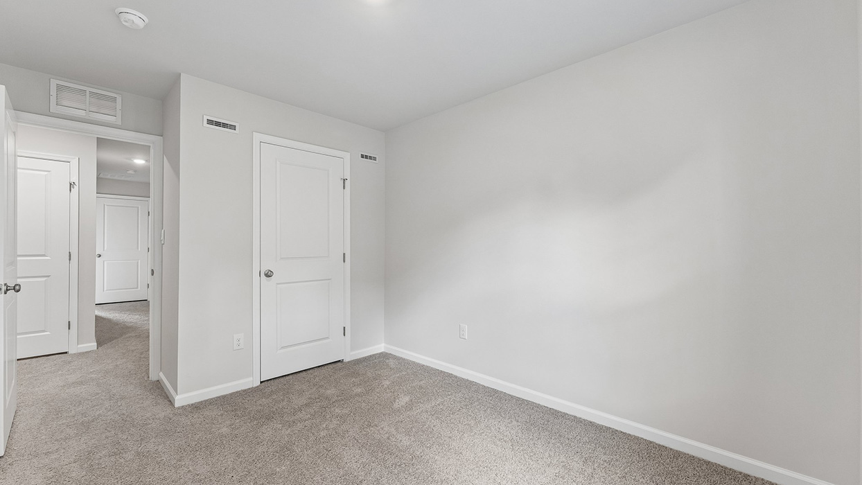 Bedroom with closet and hallway access, featuring soft carpeting and recessed lightin