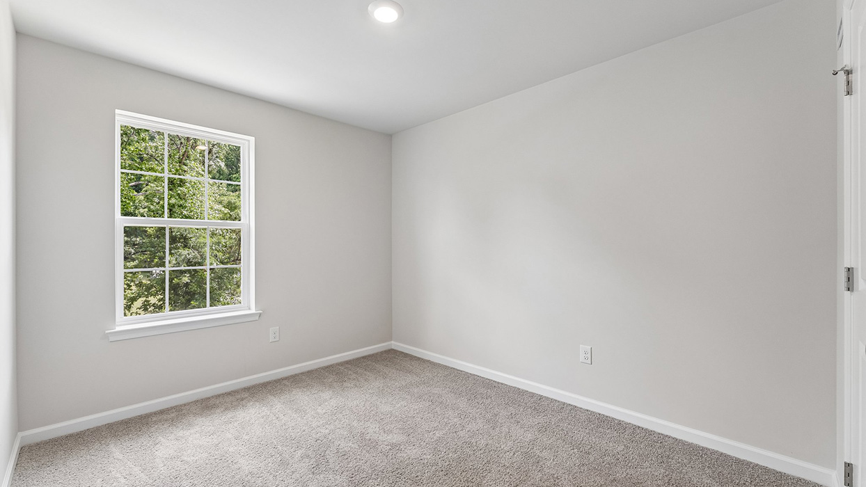 Bedroom with large window providing natural light and simple, open layout