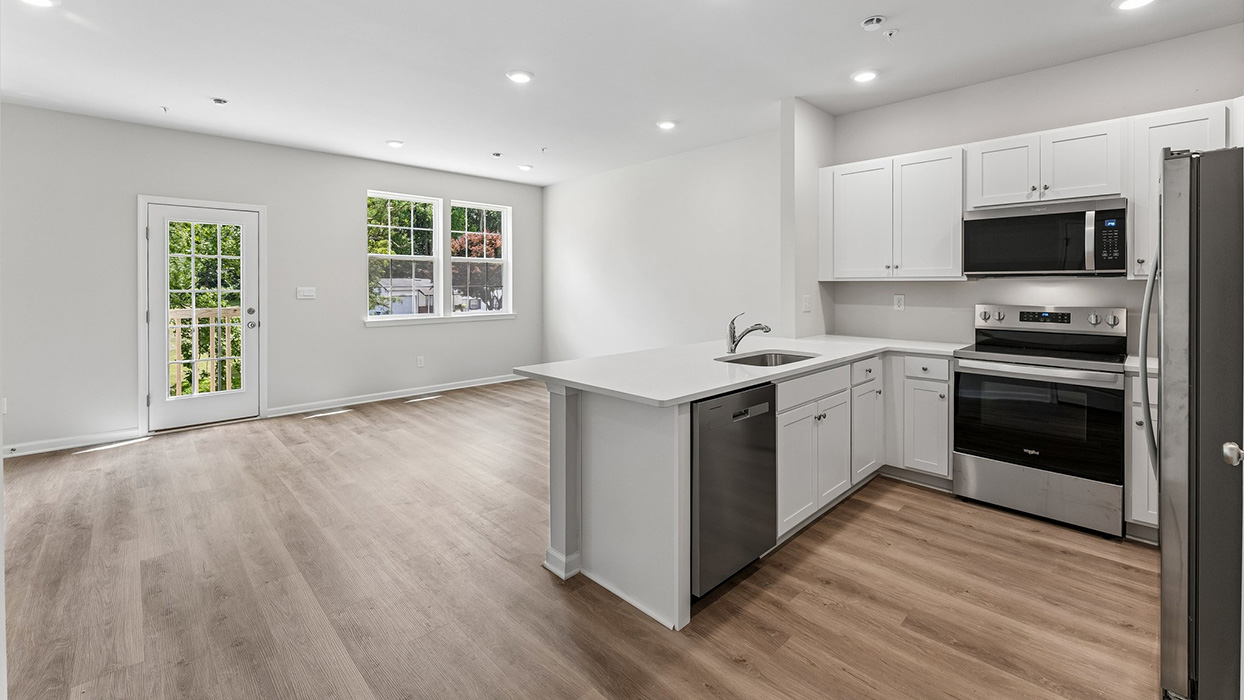 Kitchen with white cabinetry, stainless steel appliances, and center island overlooking adjacent living area