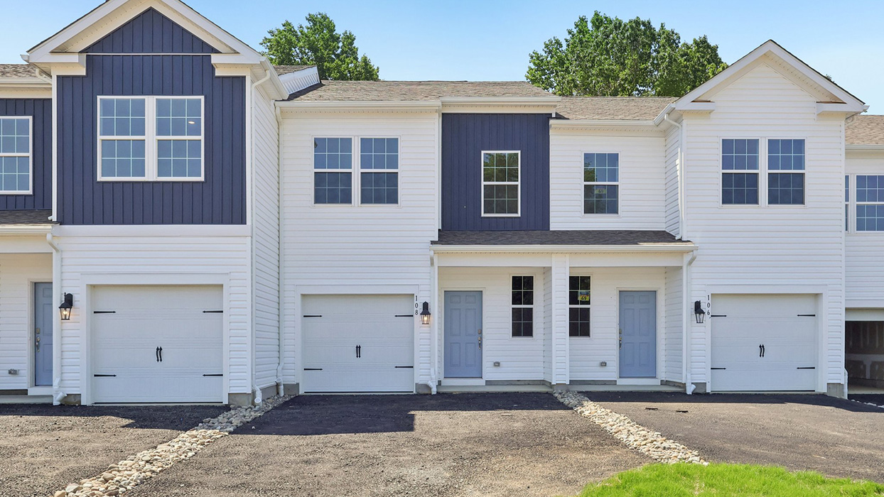 Exterior front image of the model townhome with white horizontal paneling and light blue front door