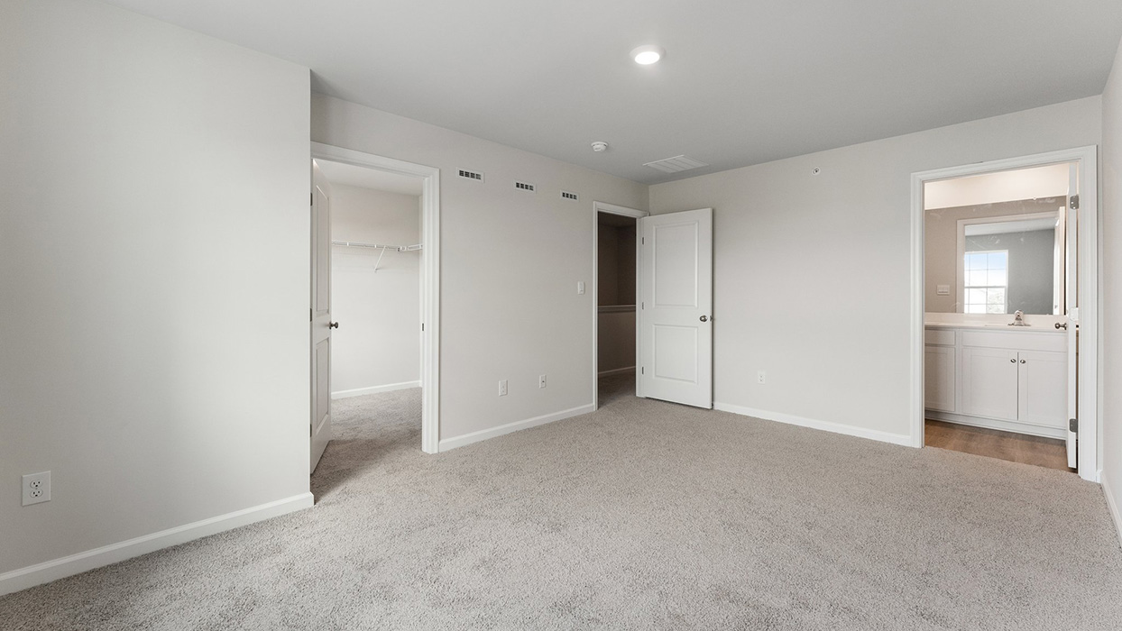 Bedroom suite with carpet flooring, walk-in closet access, and attached bathroom entry