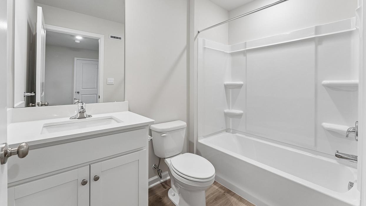 Bathroom with single vanity, mirror, and tub-shower combo featuring built-in shelving
