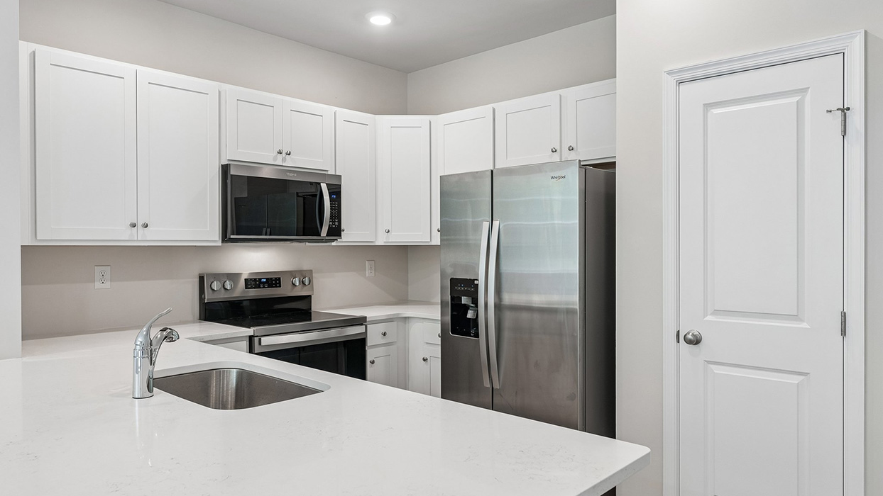 Kitchen close-up with quartz-style countertops, stainless steel appliances, and L-shaped cabinet layout