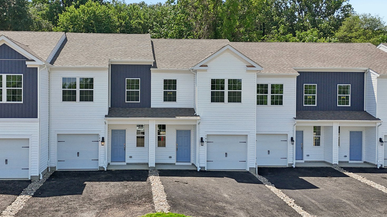 Exterior front image of the model townhome with white horizontal paneling and light blue front door