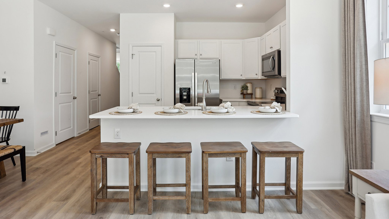The kitchen area with eat-in kitchen couner, barstool seating, and the pantry closet in view.