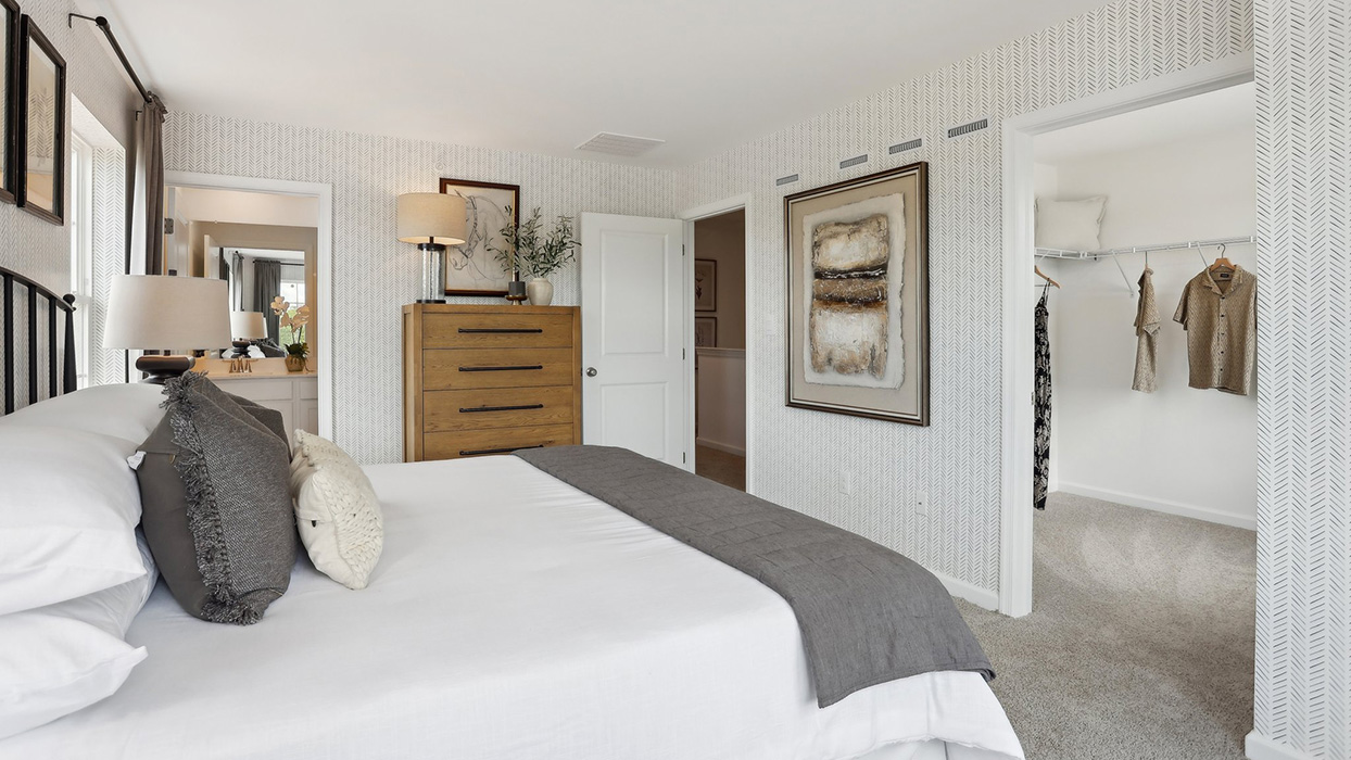A different view of the primary bedroom with peek into the walk-in closet.