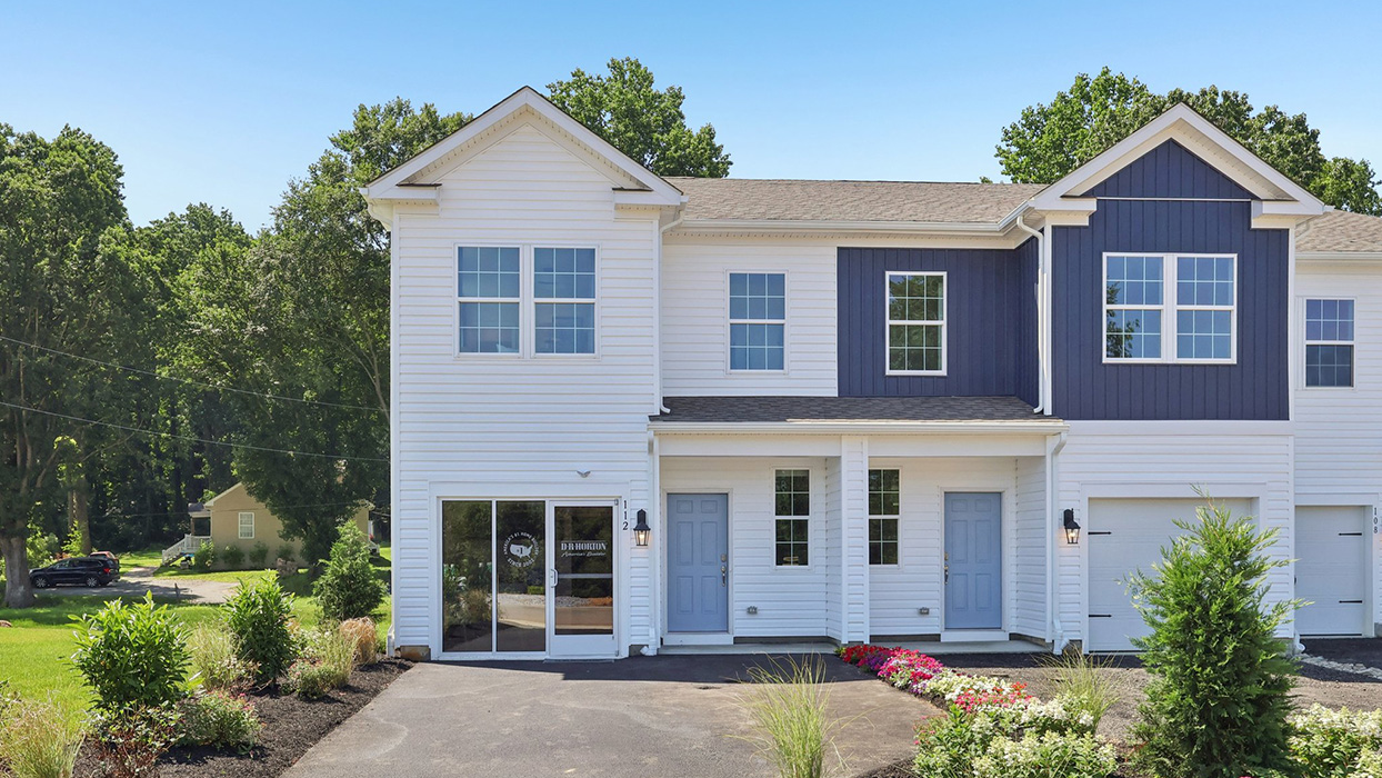 Exterior front image of the model townhome with white horizontal paneling and light blue front door