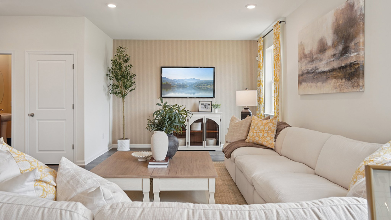 Living room with a large sectional sofa and coffee table arranged facing a wall-mounted tv above a storage console.