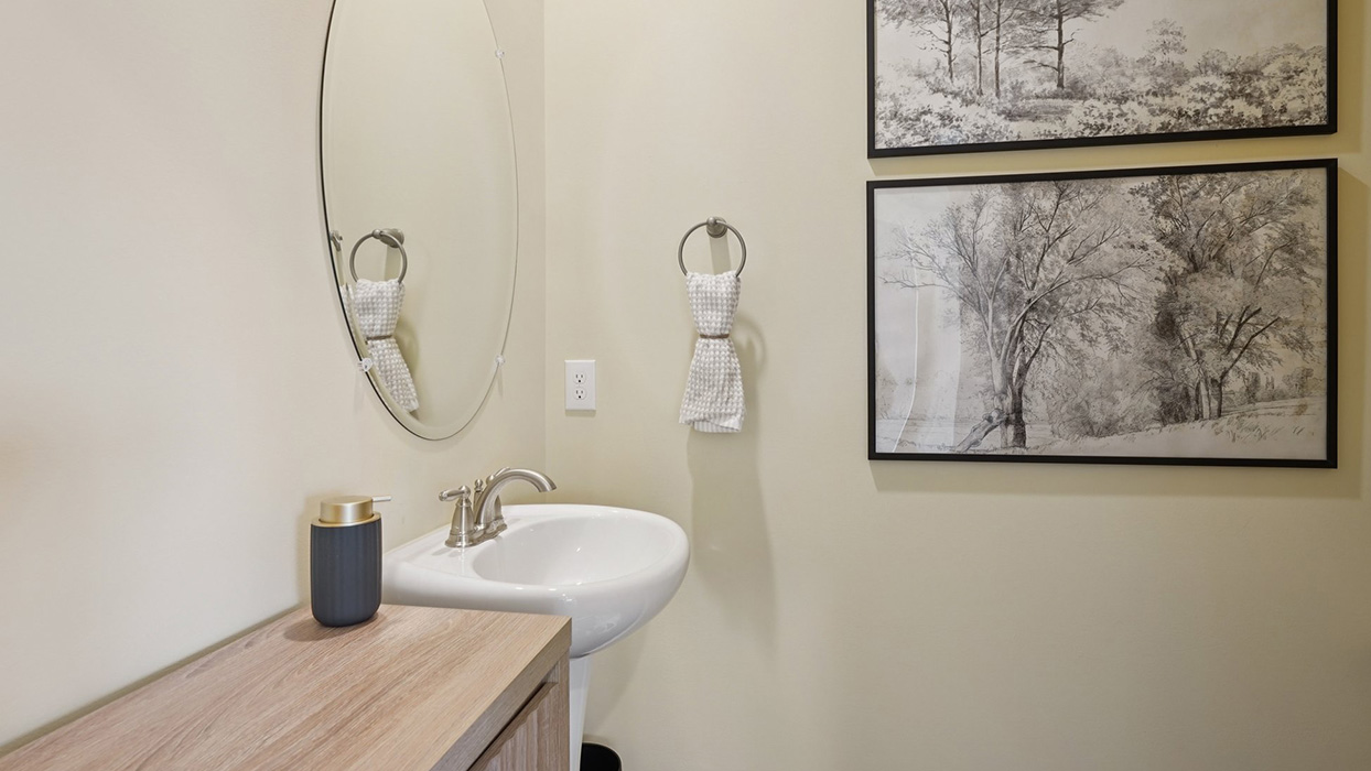 Powder bathroom with a pedestal sink, accent furniture with drawers for storage, and coordinating artwork.