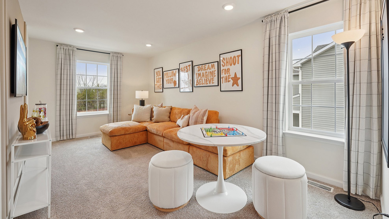The upstairs living with L-shaped couch facing a wall mounted TV.