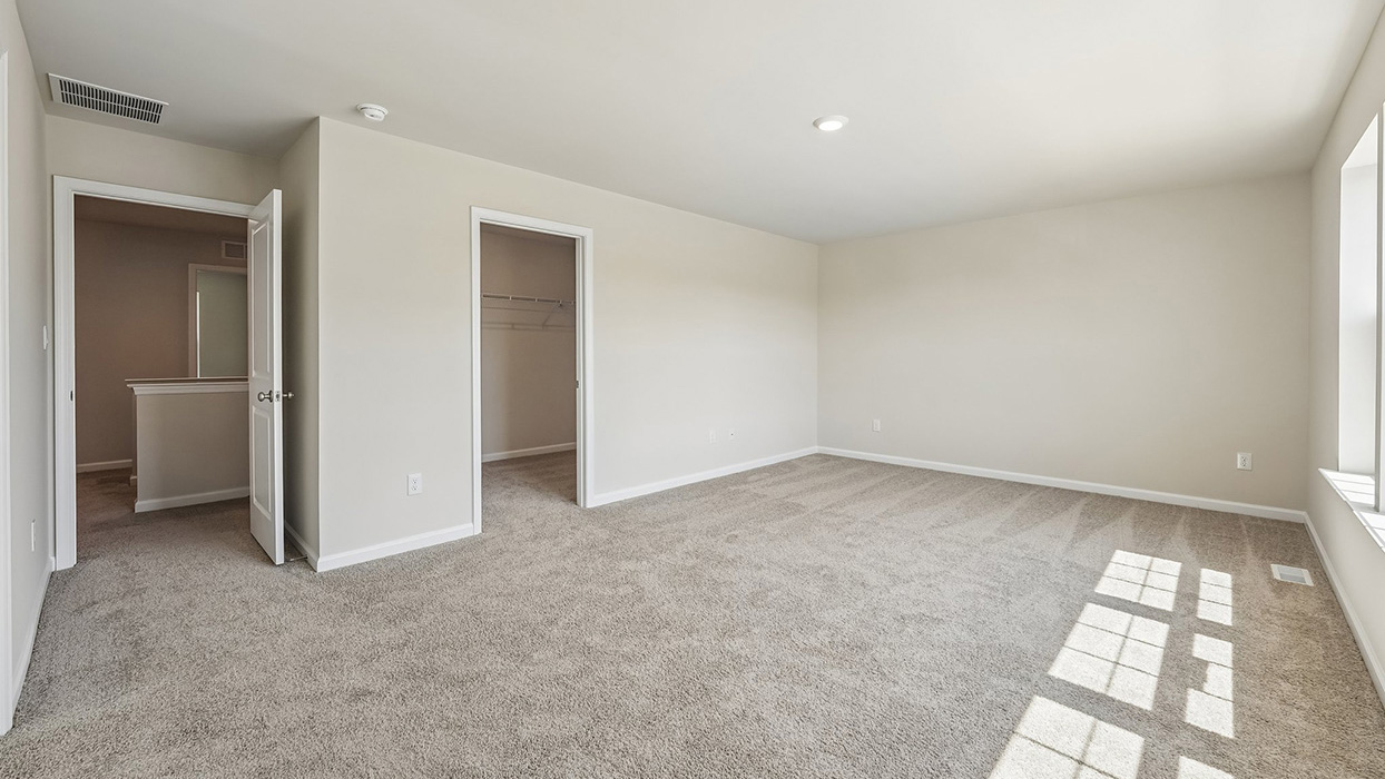 Expansive owner's suite in the Galen single-family home at Creekside Village with a spacious layout, walk-in closet, and adjoining bath.