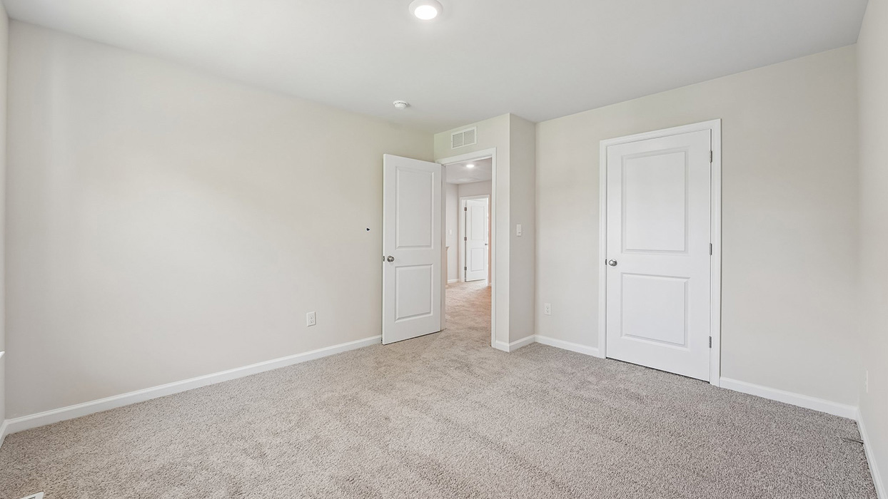 Secondary bedroom in the Galen single-family home at Creekside Village with plush carpeting, a large window, and closet storage.