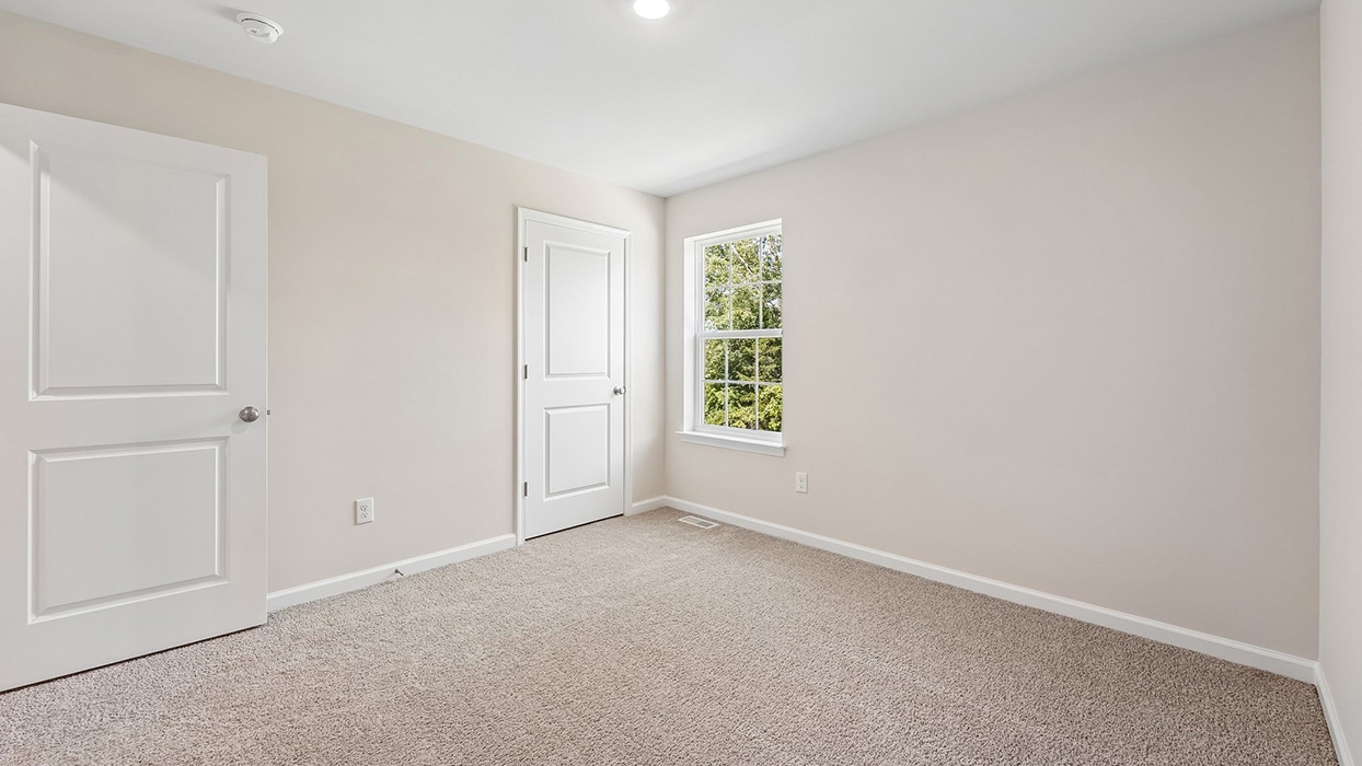 Additional bedroom in the Galen single-family home at Creekside Village with plush carpeting, a spacious closet, and large window overlooking the community.