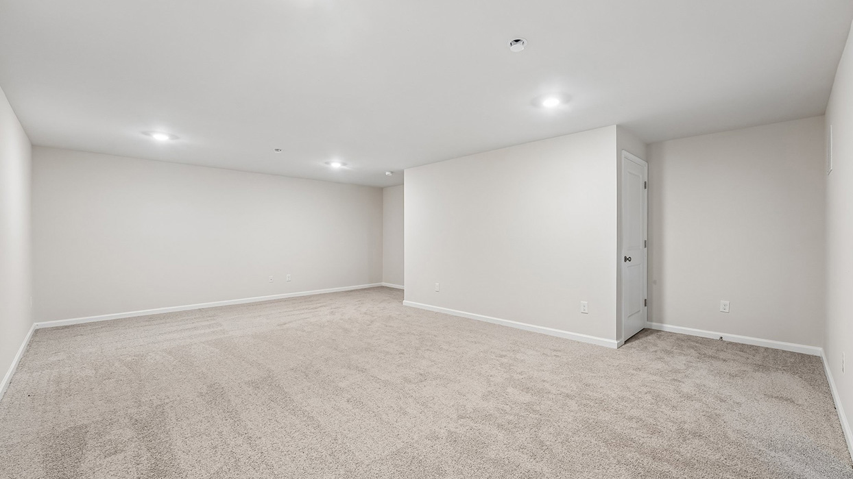 Expansive finished basement recreation area in the Galen single-family home at Creekside Village offering versatile space for entertainment, fitness, or hobbies.