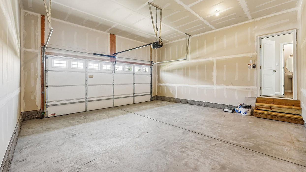 Attached two-car garage in the Galen single-family home at Creekside Village with concrete flooring, automatic garage door, and convenient interior home access.