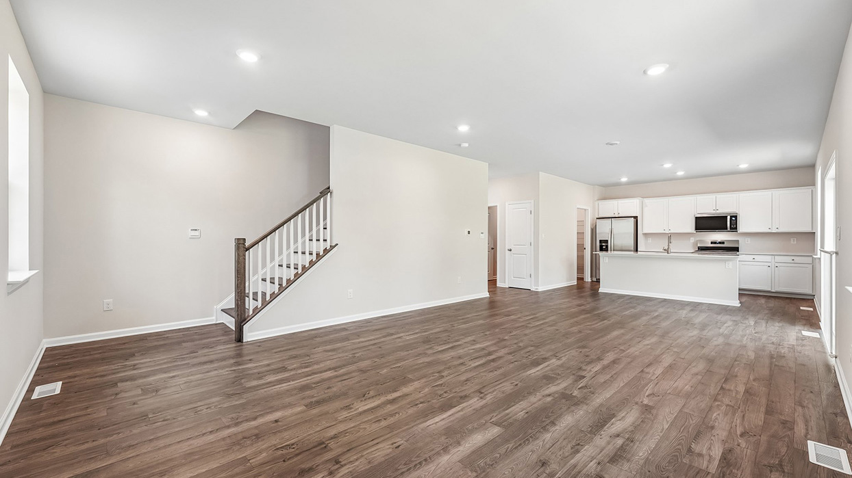 Spacious open-concept great room in the Galen single-family home at Creekside Village with luxury vinyl plank flooring, recessed lighting, and abundant natural light.