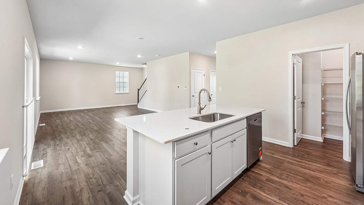Open main living area in the Galen single-family home at Creekside Village featuring a spacious great room, staircase, and kitchen with a large island.