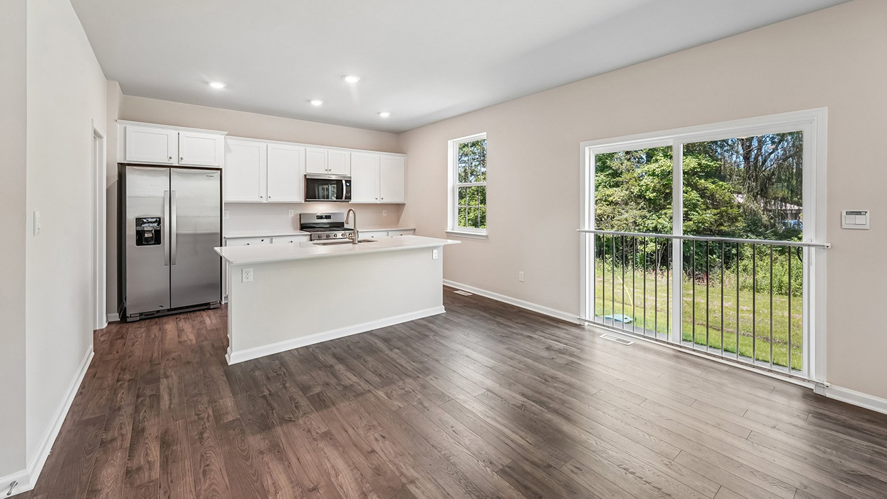 Kitchen in the Galen single-family home at Creekside Village with white cabinetry, quartz countertops, stainless steel appliances, center island, and walk-in pantry.