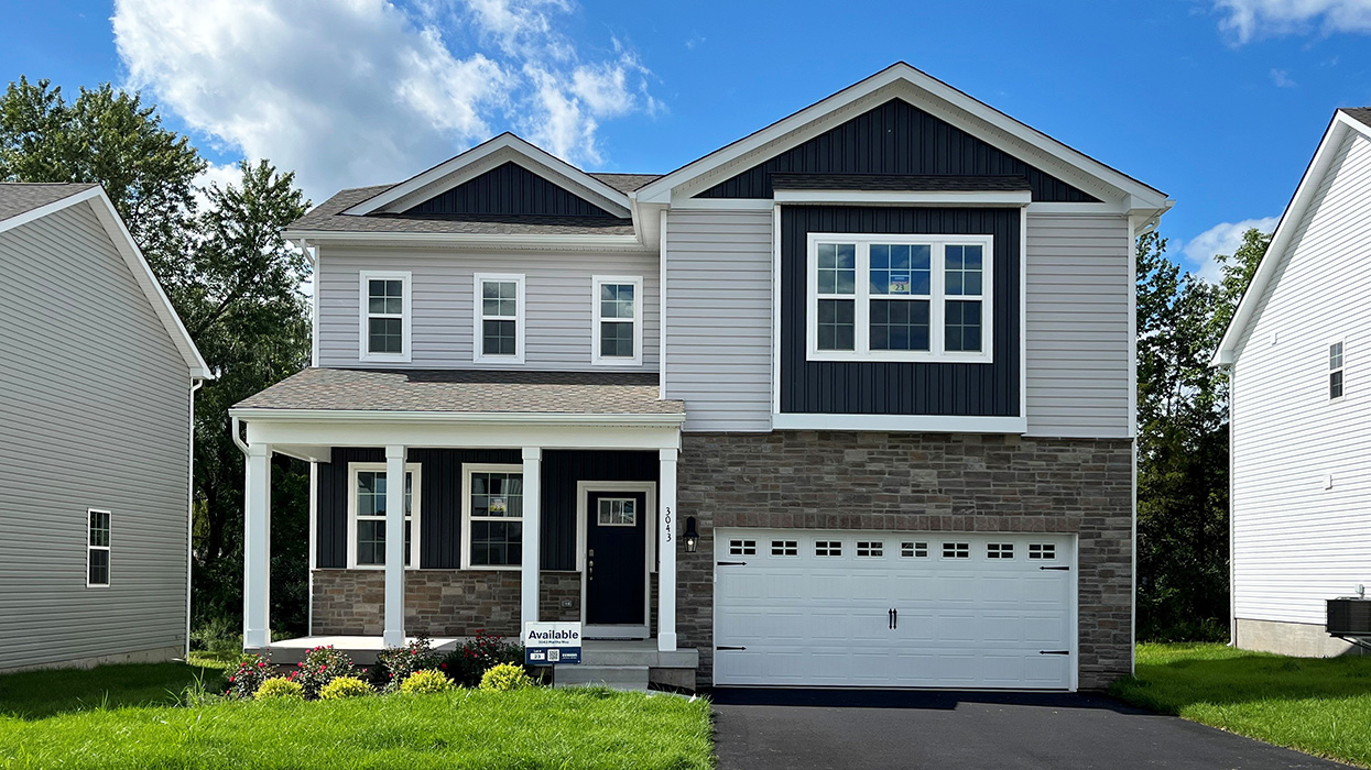 A photo of a two-story Galen home with sterling siding, ironstone board and batten accent siding, dakota ledge stone kneewall, and dakota ledge stone siding surrounding a white two car garage.