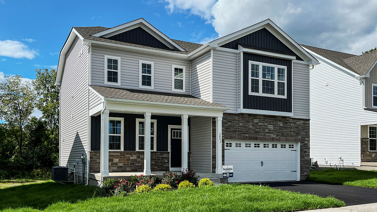 A photo of a two-story Galen home with sterling siding, ironstone board and batten accent siding, dakota ledge stone kneewall, and dakota ledge stone siding surrounding a white two car garage.