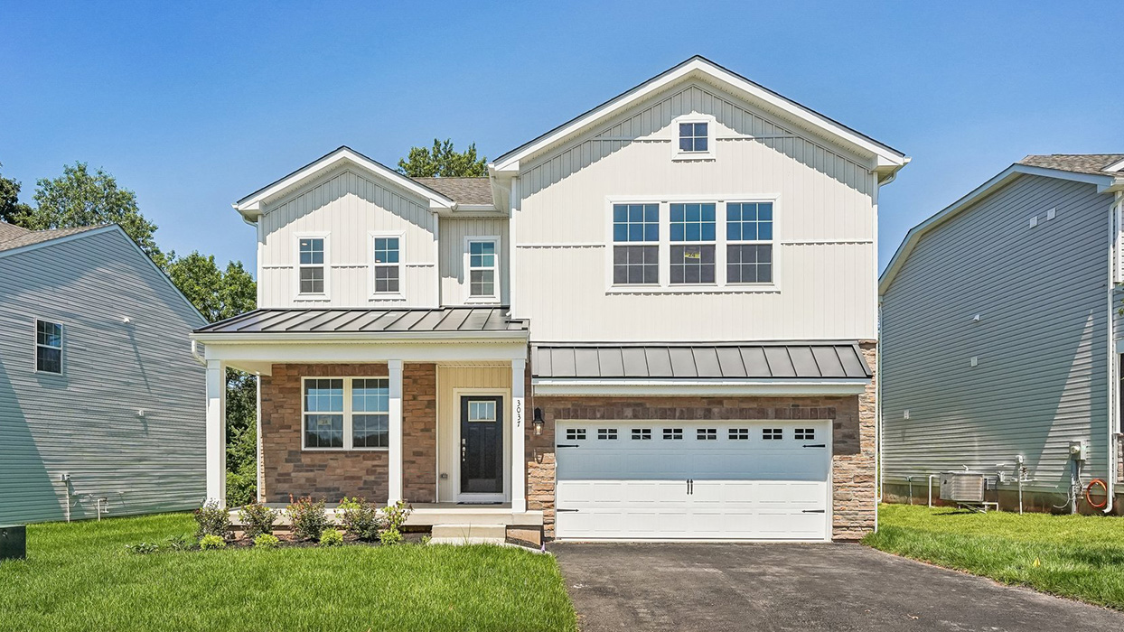 Exterior front view of Galen home with G5 elevation, featuring covered porch, stone accents, and two-car garage in Creekside Village