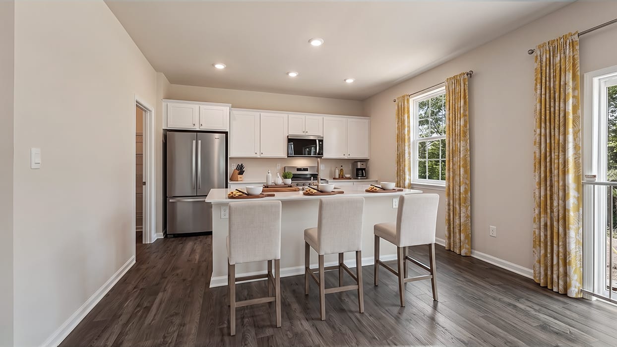 Kitchen with island breakfast bar, white cabinets, and open layout connecting to dining and living spaces