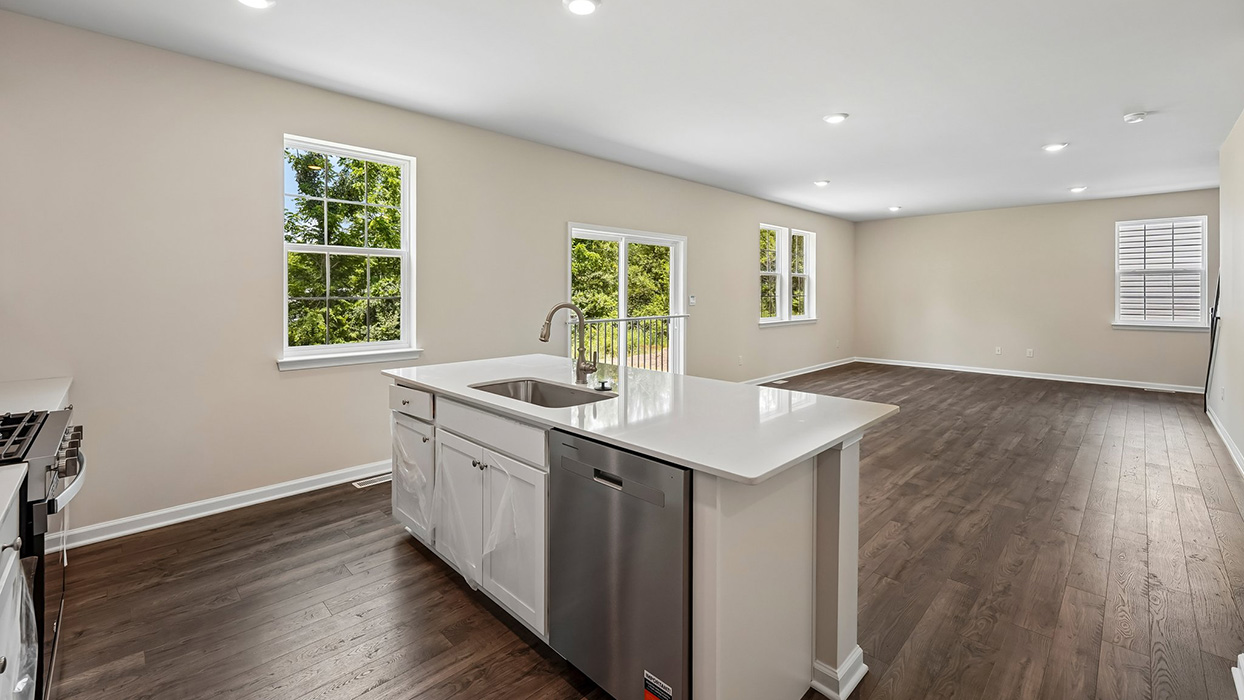 Kitchen with center island, double sink, stainless steel appliances, and open sightlines to living area