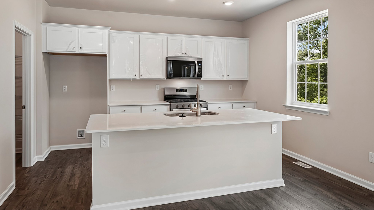 Bright kitchen with white cabinetry, large island seating, and natural light from nearby windows and sliding door