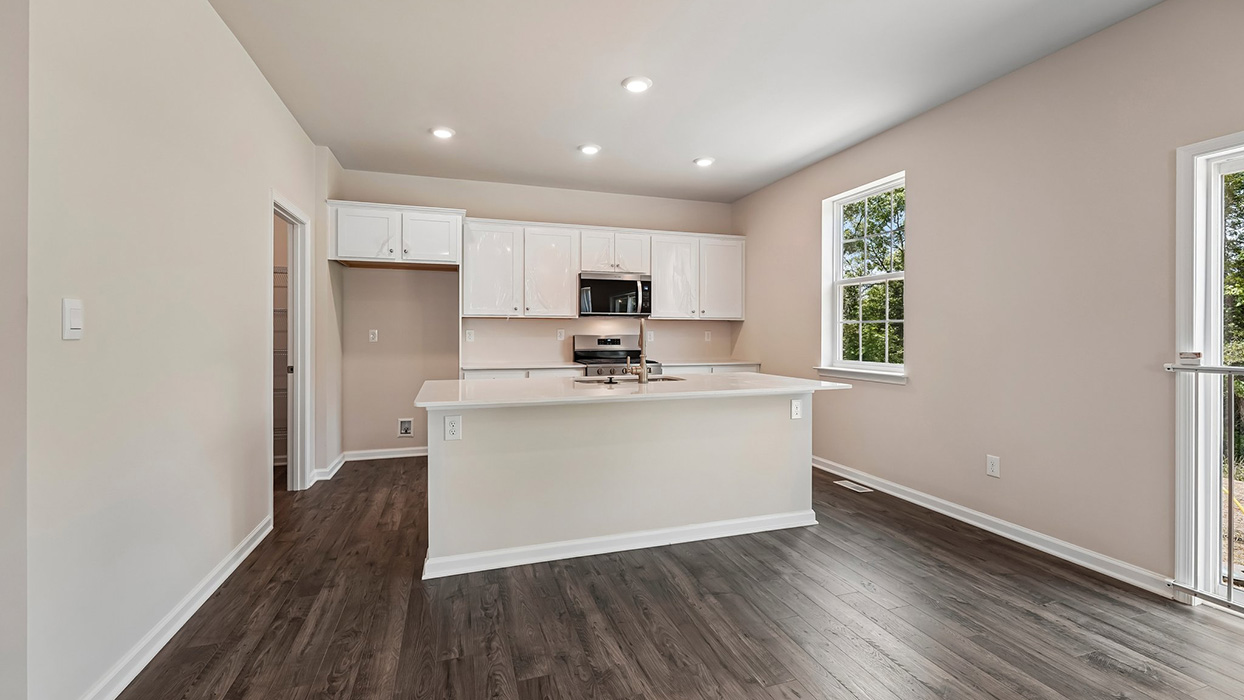 Kitchen with island breakfast bar, white cabinets, and open layout connecting to dining and living spaces