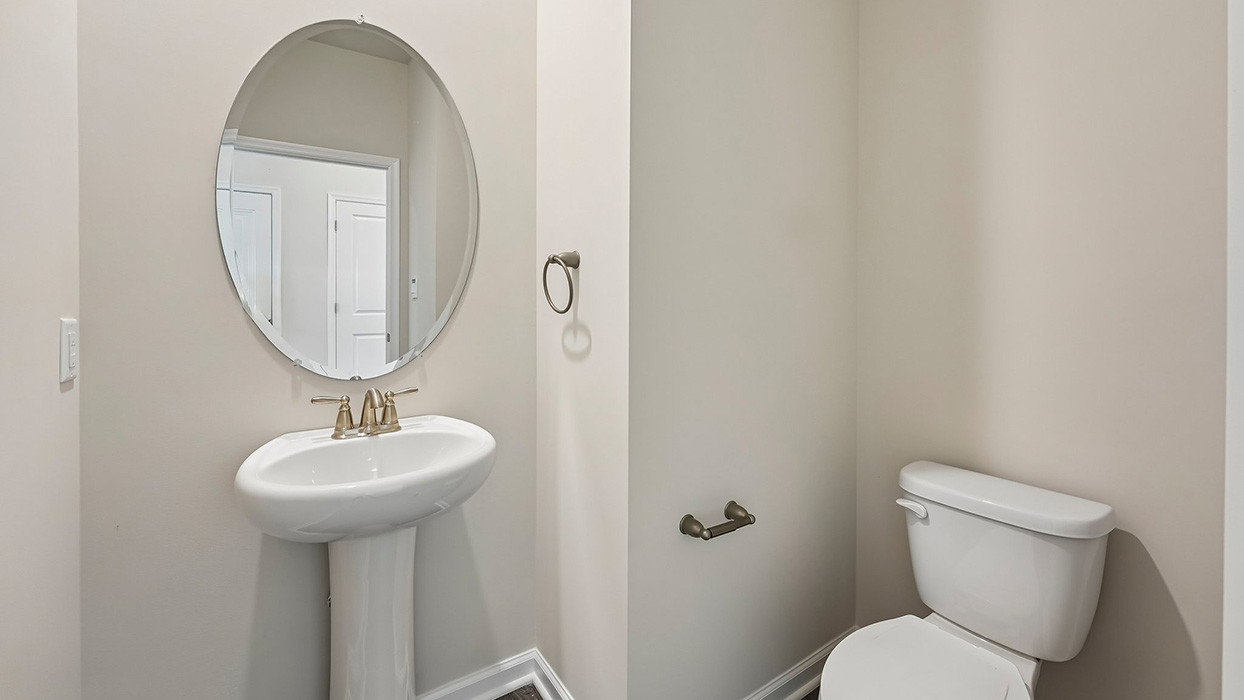 Main floor powder room with pedestal sink, round mirror, and neutral finishes