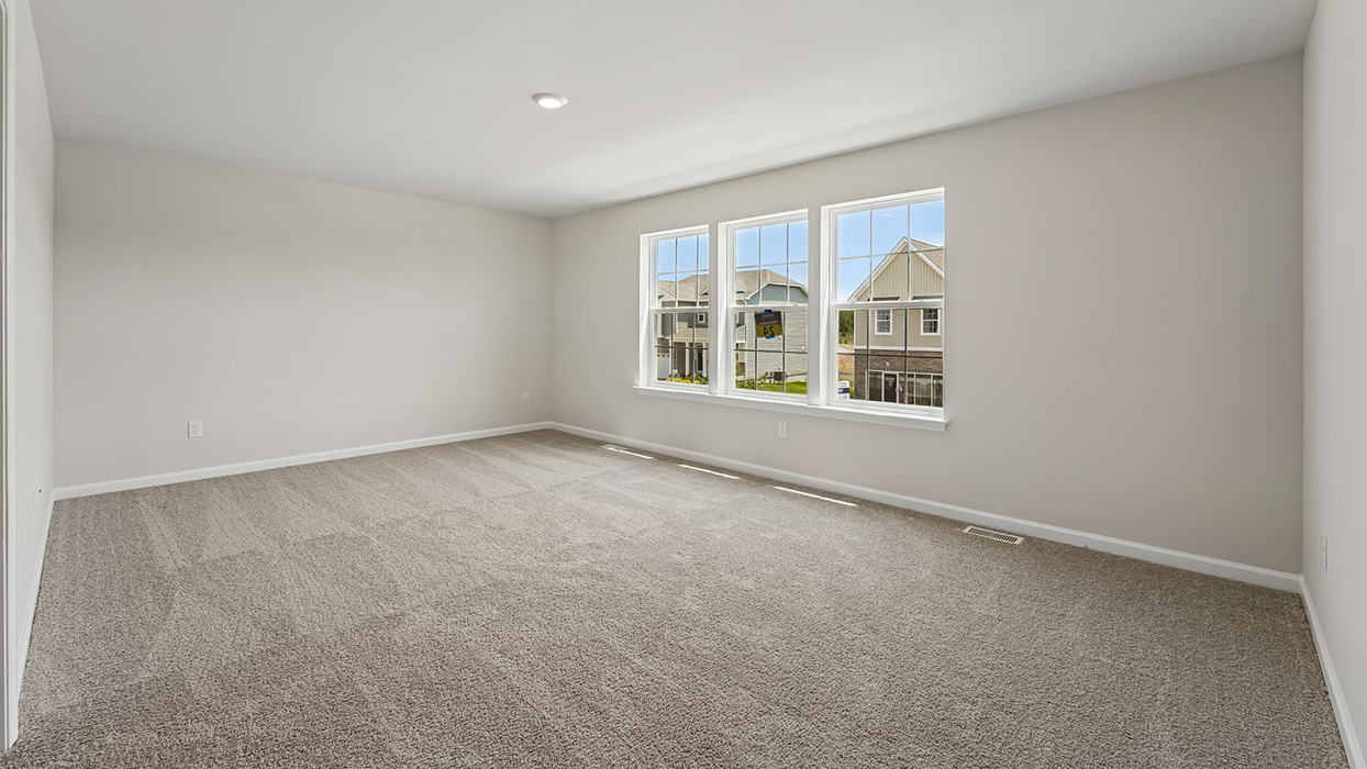 Primary bedroom with plush carpet, large windows, and spacious layout filled with natural light