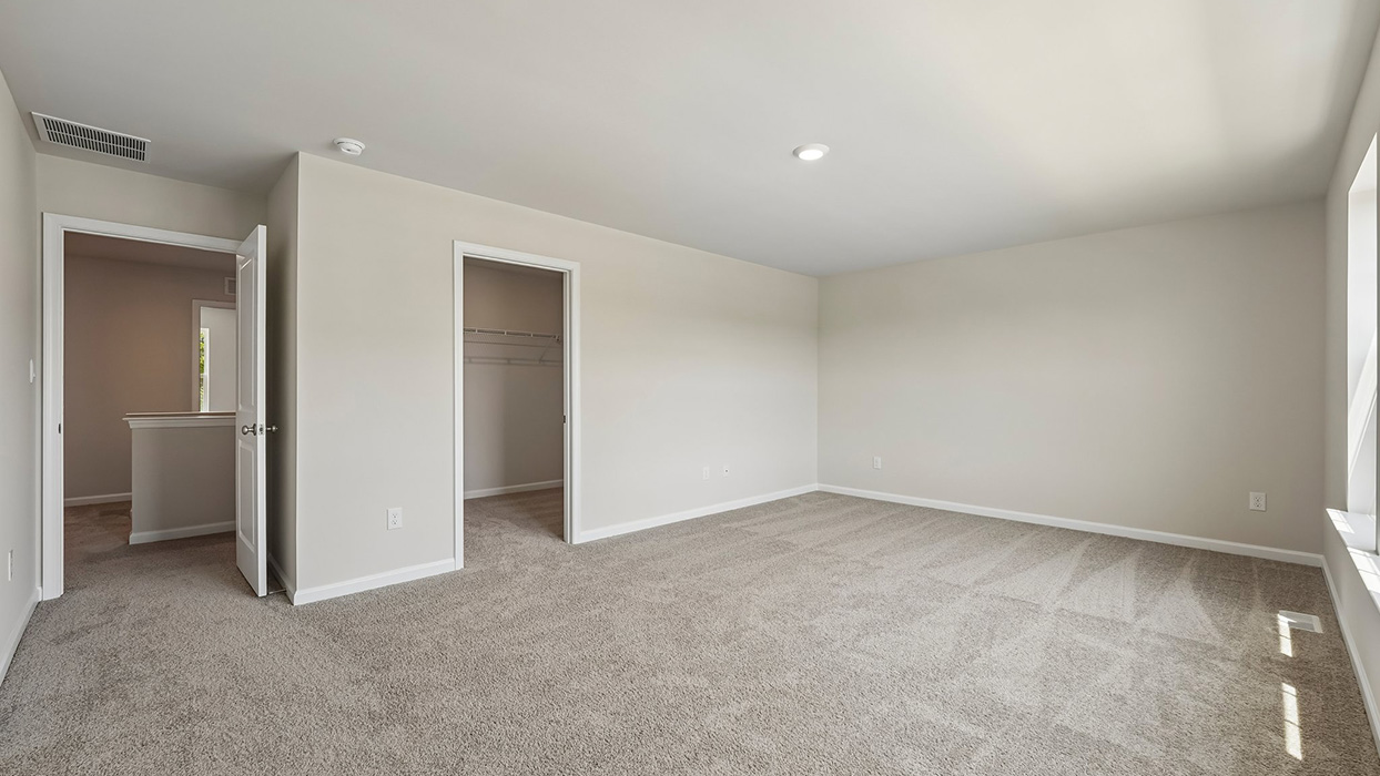 Secondary bedroom with carpet flooring, closet access, and bright natural lighting