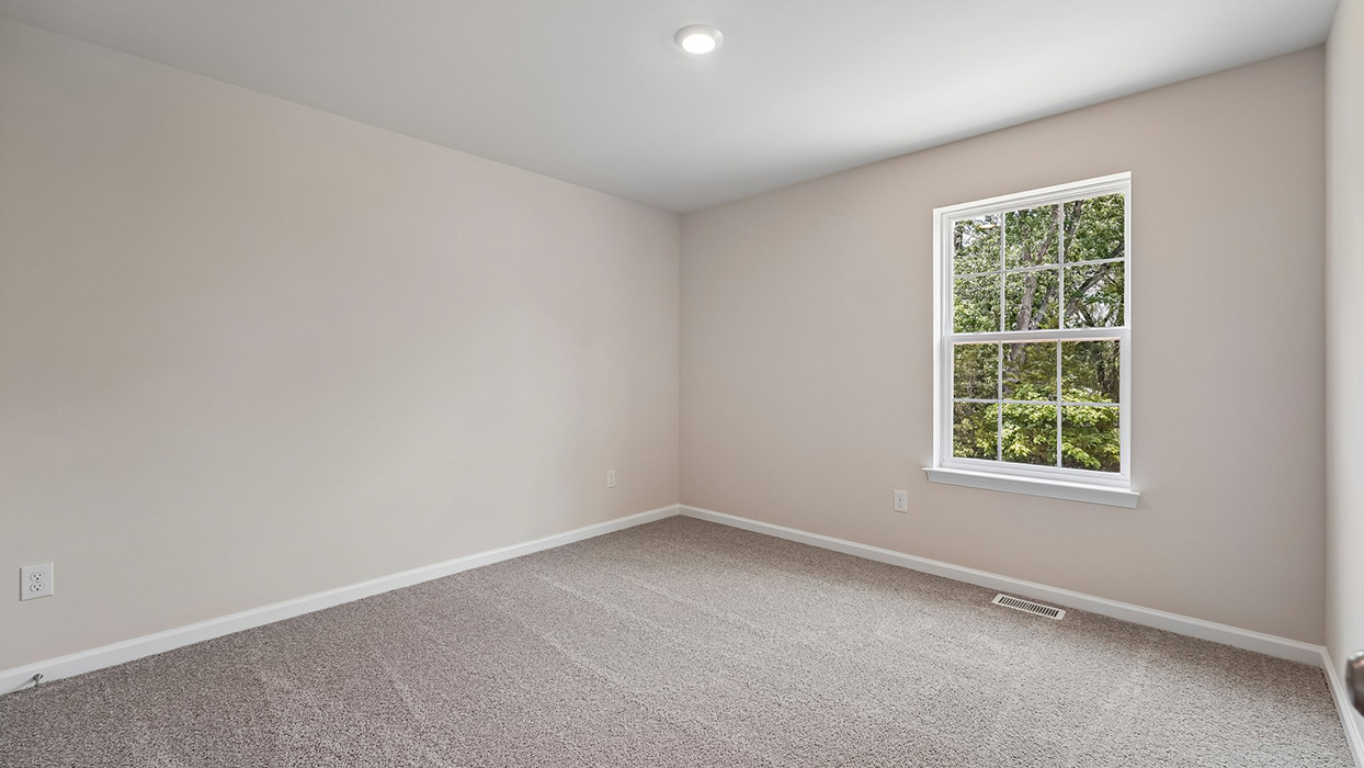 Secondary bedroom with plush carpet, soft neutral walls, and single window bringing in natural light