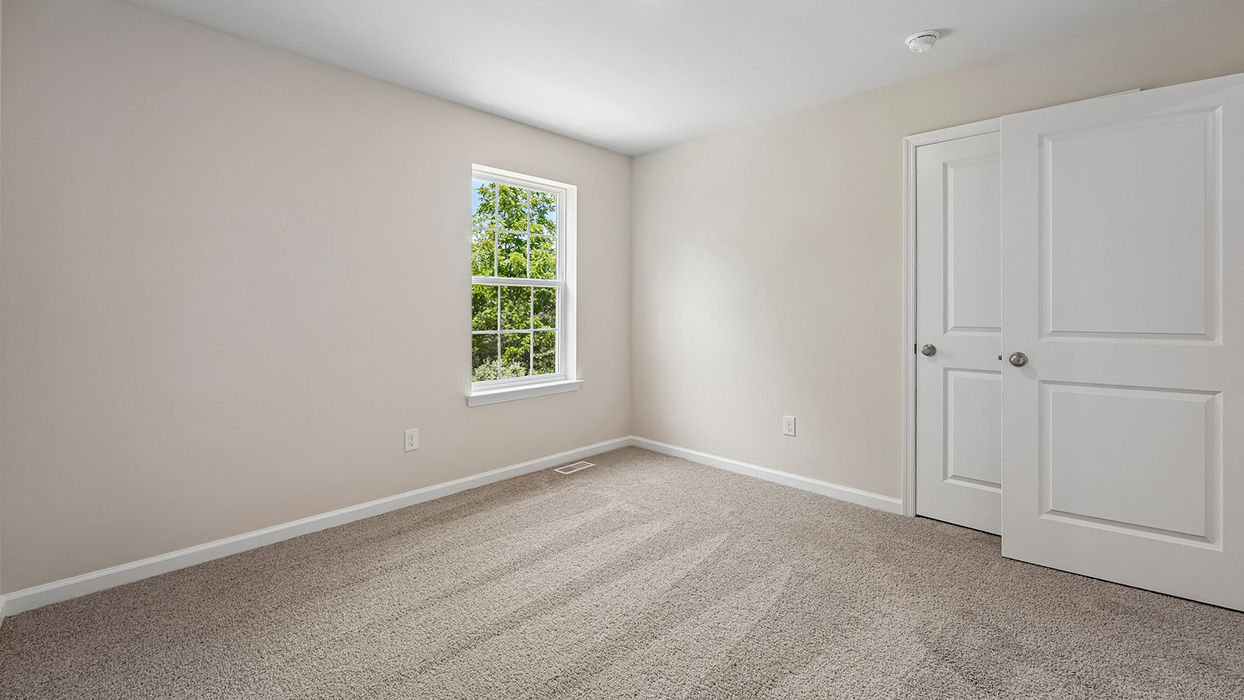 Bedroom with carpet flooring, double-door closet, and bright window overlooking trees