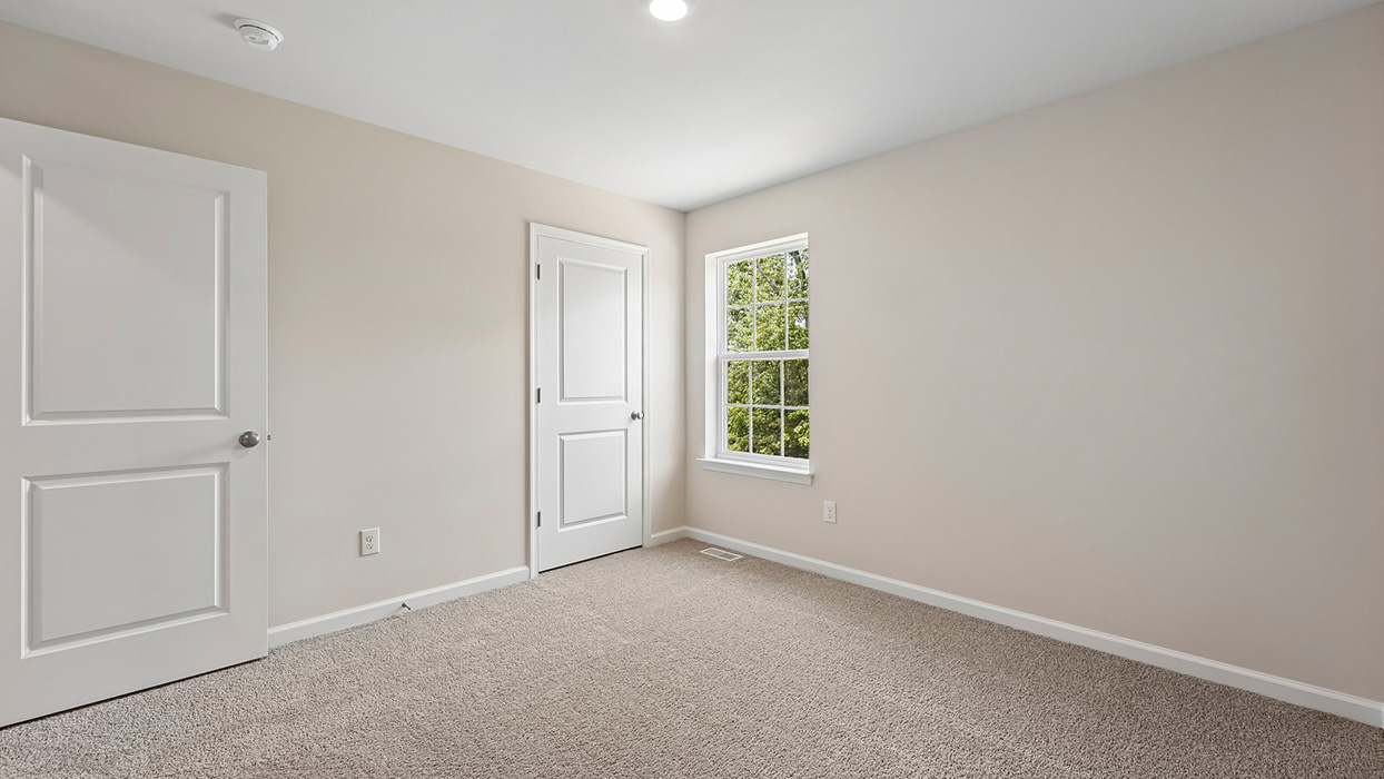 Bedroom with plush carpet, single window, and closet door, offering comfortable secondary living space