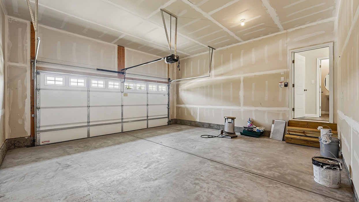 Two-car garage interior with concrete flooring, overhead door system, and unfinished walls