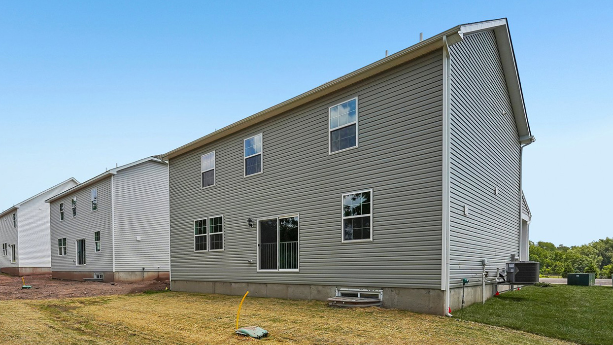 Rear exterior of Galen home with G5 elevation, featuring sliding glass door, multiple windows, and backyard lawn space in Creekside Village
