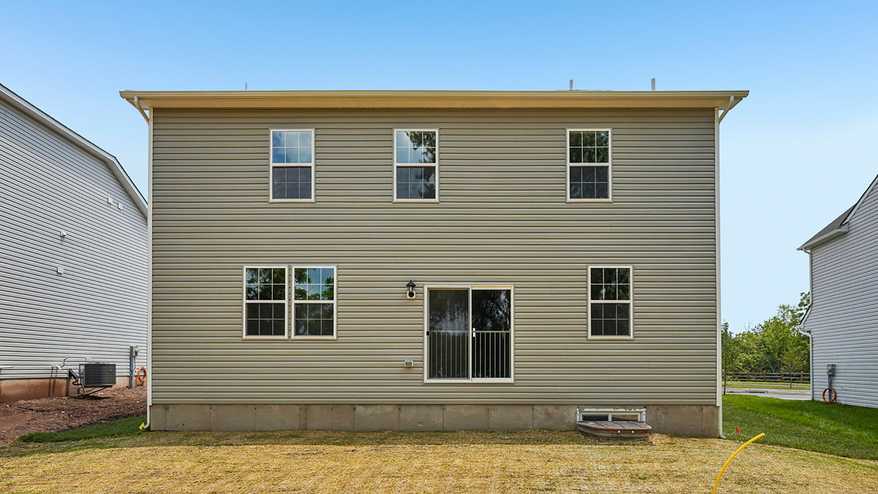 Straight-on rear exterior with sliding glass door, evenly spaced windows, and open backyard area for outdoor living