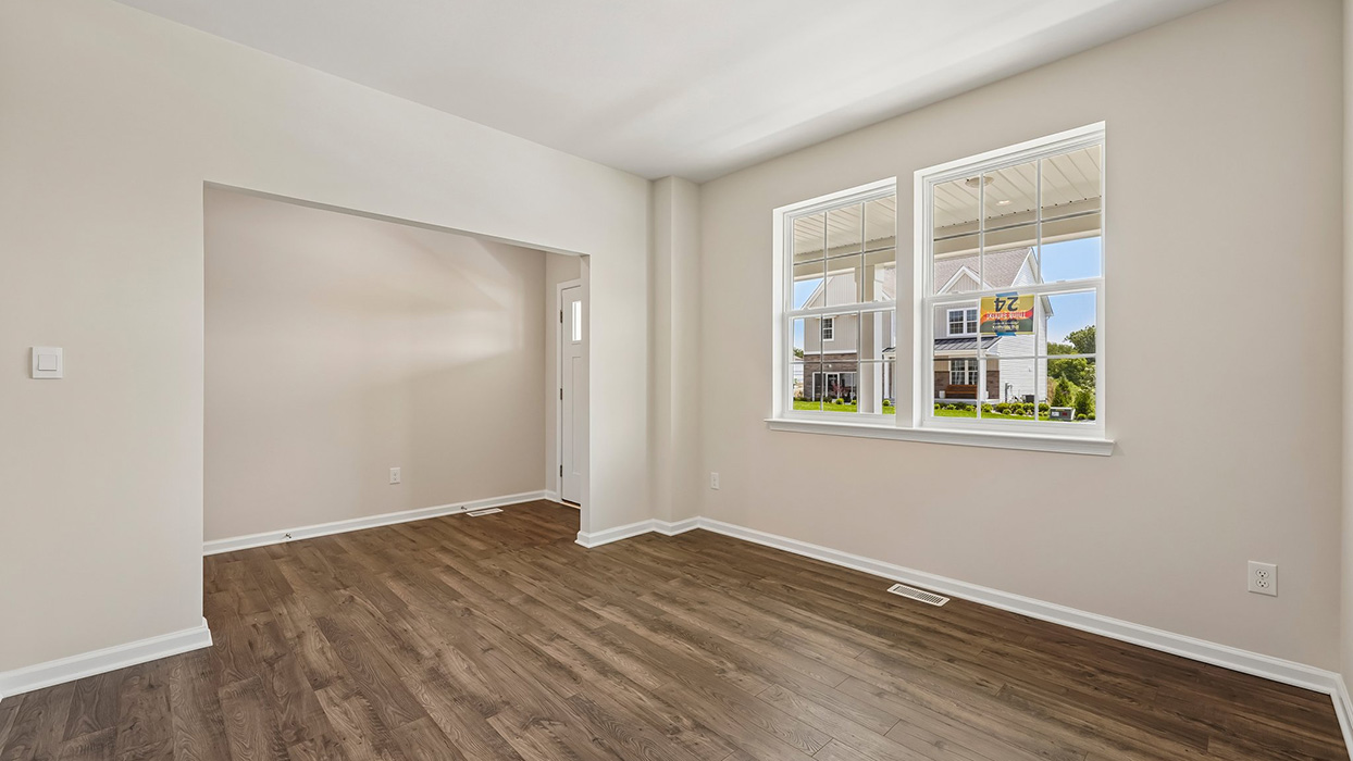 Flex space near entry with large windows, natural light, and open doorway to additional living or dining area