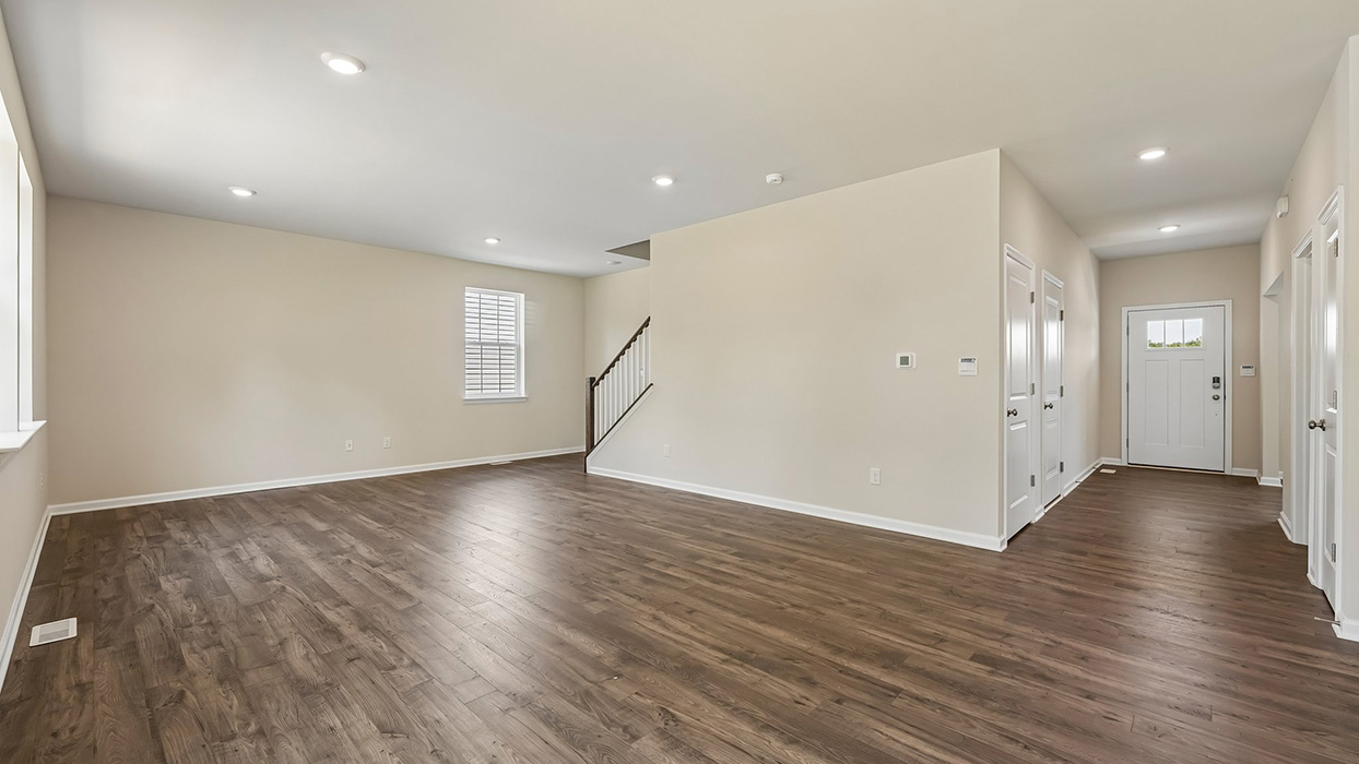 Open-concept living area with recessed lighting, staircase access, and seamless flow from entry to main living spaces